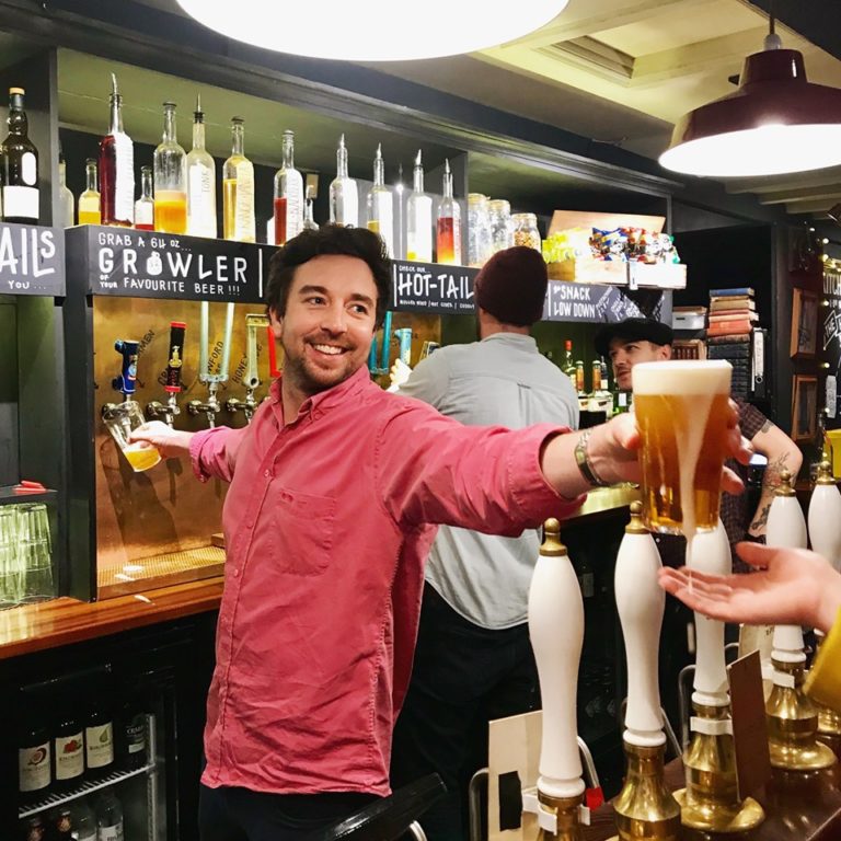 Man pouring pints behind bar