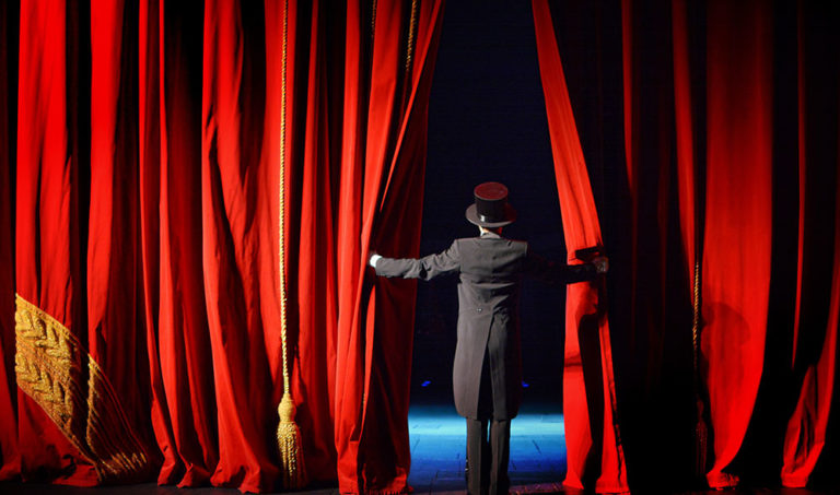 Man opening theatre red curtains